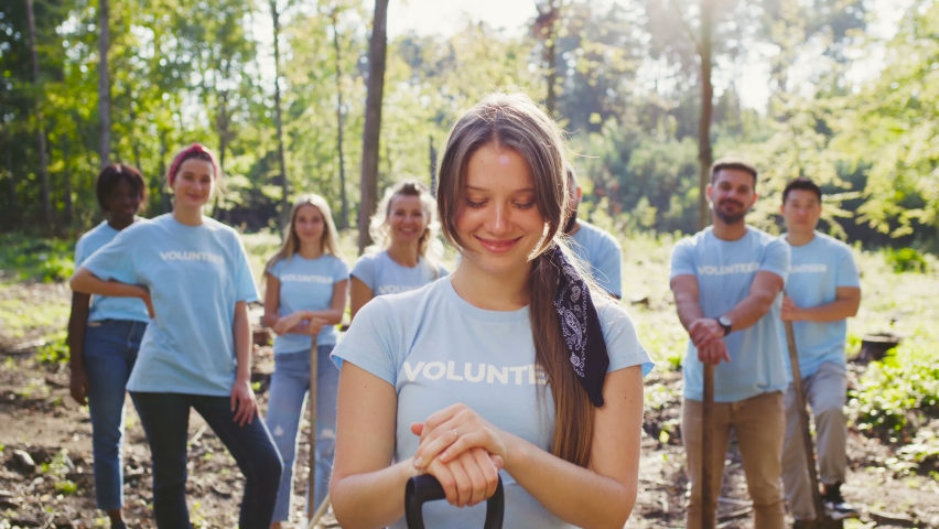 Portrait of happy woman smiling to camera and posing with shovel outdoor on summer day. Female volunteer cleaning nature from trash with multicultural team. Clean planet concept Royalty-Free Stock Footage #1081376090