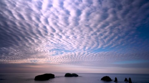 Amazing sunrise in Nameless Bay on Shikotan Island, Kuril Islands, white fluffy clouds.
