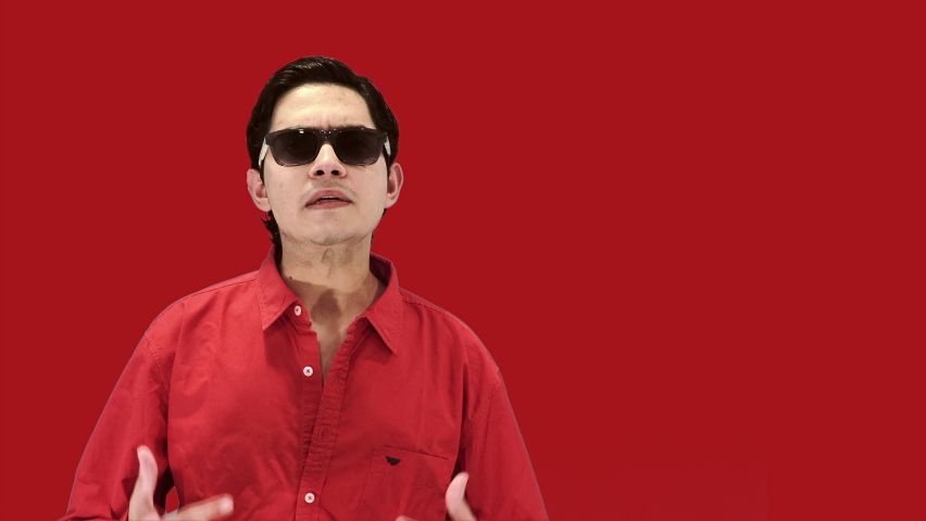 Caucasian attractive boy wearing sunglasses, wearing a red shirt and isolated with a red background. 4k ProRes
