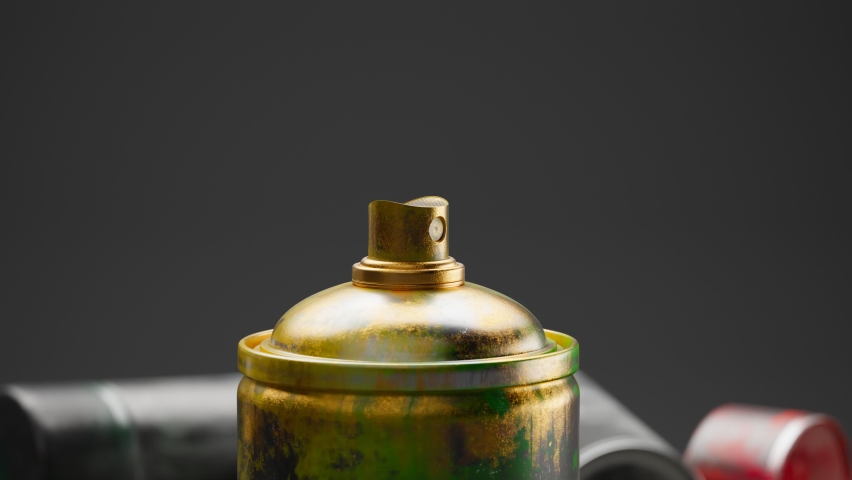 Close up on aerosol paint dispenser. Acrylic gold paint starts spraying. Multiple colourful spray paint cans are in the background. Ready to use in graffiti. Artistic purpose. Creativity in an artwork