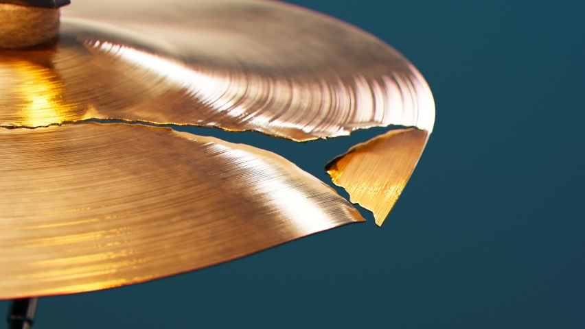 Closeup of broken cymbal for drums. Shiny hand made drum plate is dameged. Drum set. Proffesional percussion ou of use.. Musical cymbal side view. Ruined classic music instrument. Destroyed.