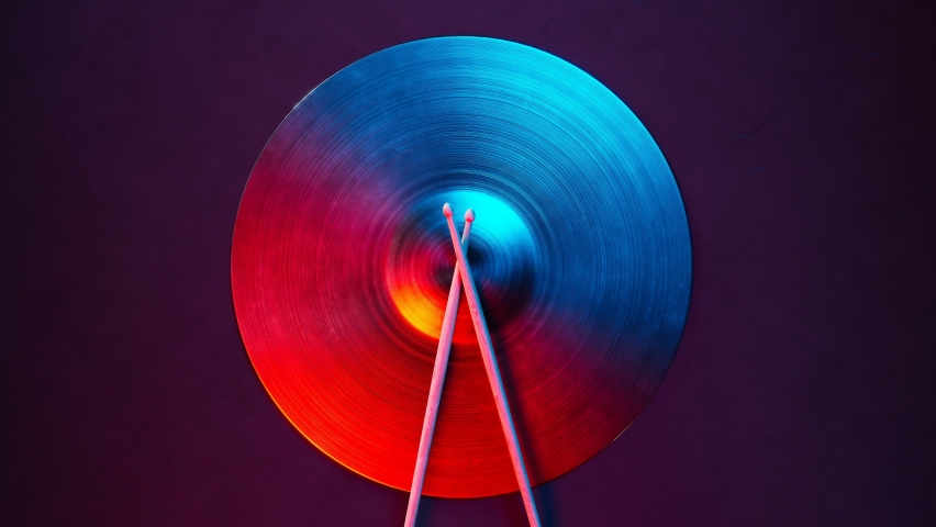 Closeup of cymbal with drum sticks. Shiny hand made drum plate. Drum set in the recording studio. Proffesional percussion. Musical cymbal top view. Elegant classic music instrument. Red and blue light Royalty-Free Stock Footage #1081384412