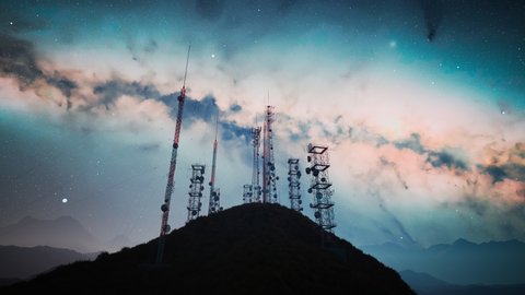 The camera flies through an antenna complex. Radio mast supports antennas for telecommunications, broadcasting, television. Tall Structures with mountains and starry sky in the background.