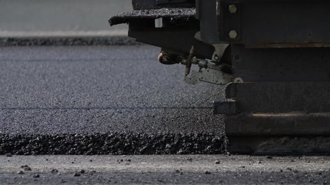 asphalt paver in the process of laying new asphalt
