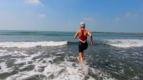 asian woman is jogging then swimming in water training for triathlon at beach