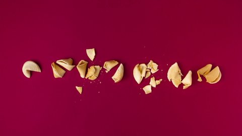 a stopmotion of a box full of fortune telling cookies opening, cookies dancing, form a line and crack one after another