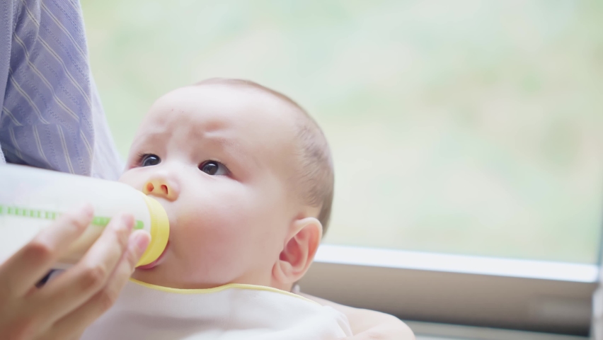 Mother suckling her baby with a feeding bottle. Royalty-Free Stock Footage #1081391684
