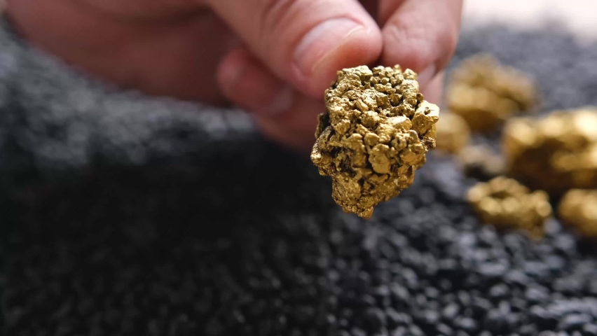 The hands of men are looking at the gold ore in their hands from the mine
