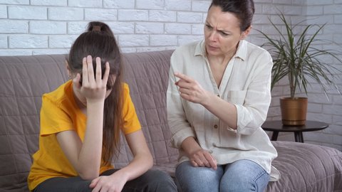 Mother with moralizing lessons. A view of a stressed mother talking a moralizing lesson to her young daughter in the room.