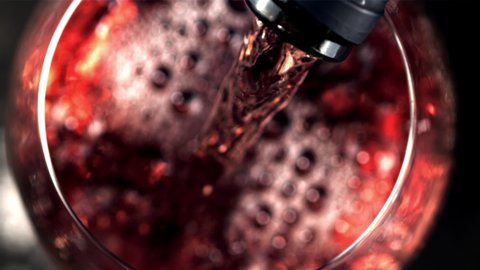 Super slow motion red wine pours with air bubbles into the glass. Macro background. Top view.Filmed on a high-speed camera at 1000 fps. High quality FullHD footage
