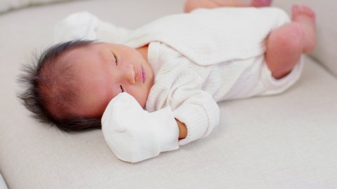 Newborn baby hiccups after feeding milk.Asian newborn lying on white bed and frequently gets hiccups.Newborn Baby Health Care Concept