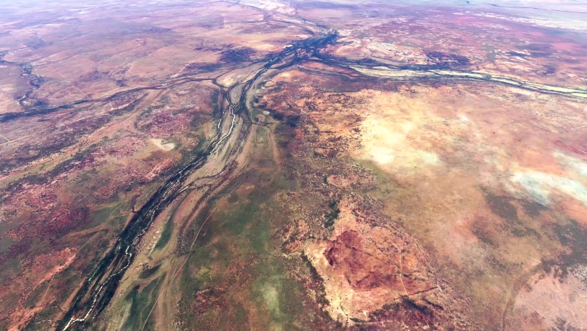High altitude view from airplane of Australian desert located in central Australia showing the dry sandy and rocky natural environment with typical yellow red colours 4k quality animation Royalty-Free Stock Footage #1081399604