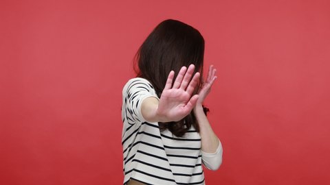 Portrait of woman grabbing nose with fingers, feeling unpleasant smell, shocked with disgusted fart, wearing casual style long sleeve shirt. Indoor studio shot isolated on red background.
