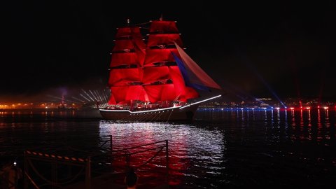 Russia, St. Petersburg - June 26, 2021: Holiday SCARLET SAILS 2021. Sailboat with scarlet sails sails on Neva River. Fireworks and beams of searchlights in White Nights for high school graduates.