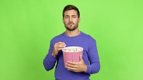 Handsome man holding a bowl of popcorns doing surprise gesture over isolated background