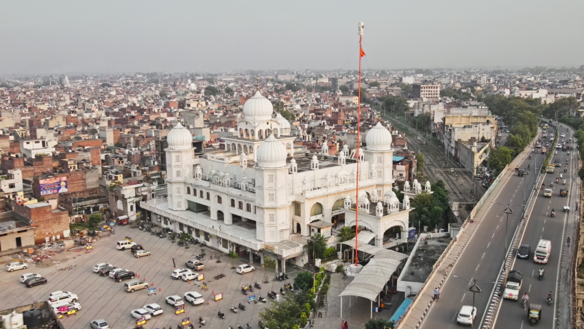 Aerial view of a Gurudwara (Sikh Temple) situated amidst Ludhiana city of Punjab, India. Drone shot of a Gurudwara situated alongside Jammu-Kanyakumari national highway (Grand Trunk Road).  Royalty-Free Stock Footage #1081408646