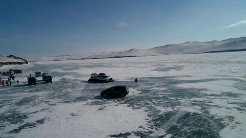 Khuzhir, Russia- March 2, 2021: Aerial view on the hovercraft drifting and driving on cracked snowy ice of Baikal. Drone follows the hovercraft and flies over the vehicle. Beautiful winter landscape