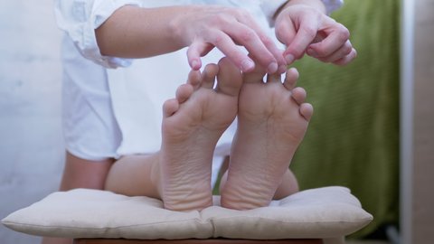 Hands of a Masseur, Therapist are Massaging Bare Feet, Soles of a Child. Pressing acupuncture points of foot with fingers. Reflex massage. Effective treatment, improves blood circulation in soles. 4K.