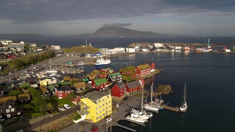 Beautiful cinematic aerial footage of the city of Torshavan in the Faroe Islands and its classic colorful houses, red Goverment building with grass on the roof, and marina