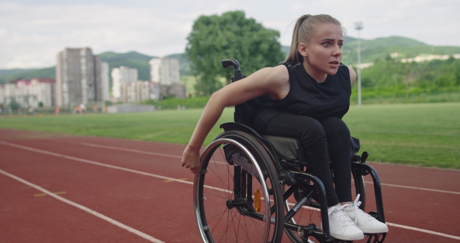 A female person with disabilities riding a wheelchair on a training track | Shutterstock HD Video #1081423115