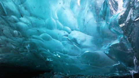 Panning shot blue colored Ice Cave Glacier and lighting sun behind the icy wall - Visiting Nature of Iceland