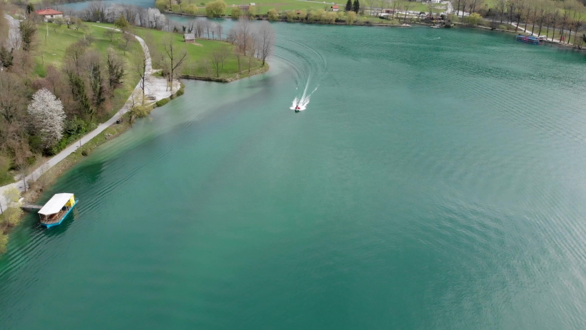 Aerial shot of firefighters on urgent ride in motorboat on lake on spring day