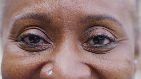Close up shot of black womans eyes as she looks to camera and smiles