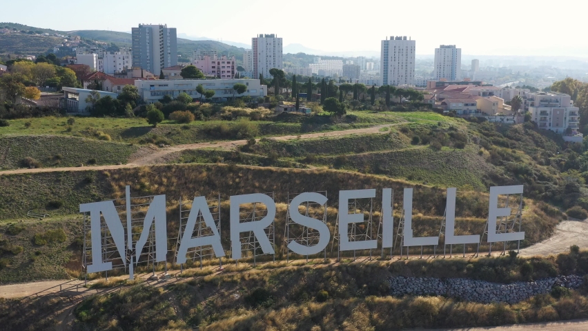 France, Marseille, giant letters like the Hollywood sign at the top of Grand Littoral hill. Backward drone aerial view. Former city of Bernard Tapie.