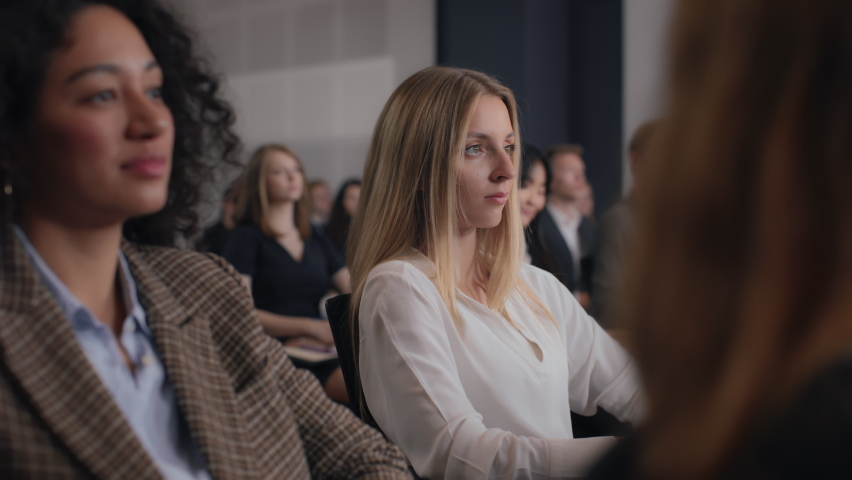 Group of people listens speech at business conference. Stage talk at summit meeting in crowded modern hall. Caucasian woman training at economy forum. Business work of sitting female person close-up Royalty-Free Stock Footage #1081436714