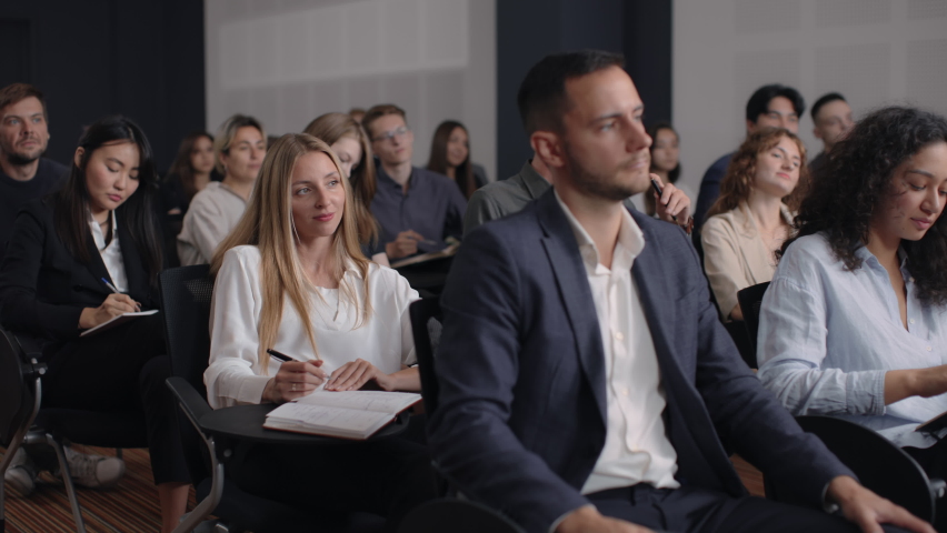 Group of people listens speech at business conference. Stage talk at summit meeting in crowded modern hall. Caucasian woman training at economy forum. Business work of sitting female person indoors Royalty-Free Stock Footage #1081436717
