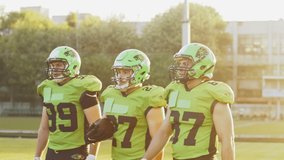 Waist up portrait view of the athletic football players in protective gear walking along the playing field with confident emotions. American football training day concept - Powered by Shutterstock - Get 15% off with code: PIKWIZARD15