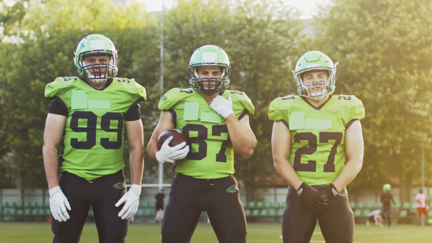 Confident and brave football players lining up and looking at the camera while posing together after successful game. Sport concept