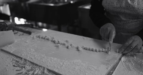 Woman kneads and preparing dough for fresh made gnocchi inside pasta factory
