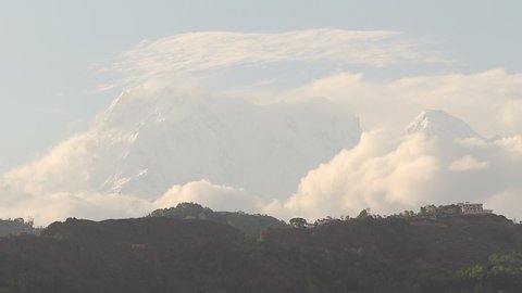 Beautiful sunset view of clouds rolling over the Himalayas in the Pokhara valley of Nepal. Timelapse of Mt. Machchapuchhre or Fishtail during morning hour.