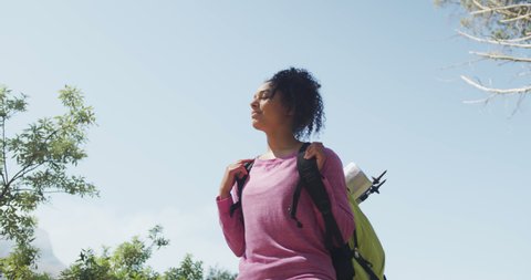 Smiling biracial woman looking away and hiking in countryside. healthy, active lifestyle and outdoor leisure time.