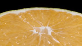 Video of sliced spinning tangerine on black background