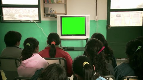 School Children in Classroom Watching Old TV with Green Screen. You can replace green screen with the footage or picture you want. You can do it with “Keying” effect in After Effects. 4K Resolution.