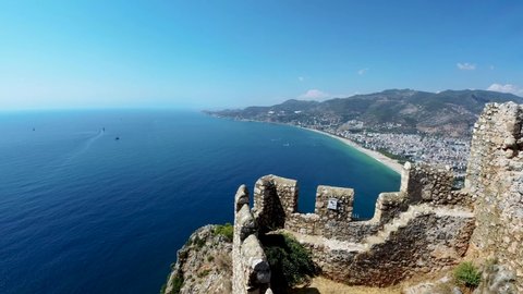 Turkey - Antalya: Wide angle Aerial drone view from the Citadel of Alanya on west part of modern city with a famous Cleopatra Beach against city and mountains. Sea panoramic view from top.