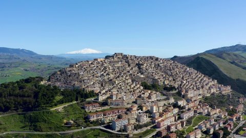 Aerial shot with drone of the village of Gangi with a view of the Etna volcano. Typical Sicilian village. Nature on the Madonie in winter. Wheat fields.