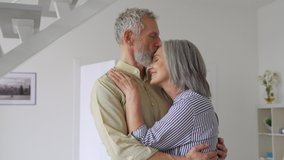 Dreamy senior adult mature couple standing hugging, bonding, thinking of good future. Carefree cheerful mid age old husband hugging wife looking away dreaming, enjoying wellbeing love in new house. - Powered by Shutterstock - Get 15% off with code: PIKWIZARD15