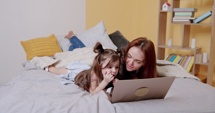 Woman and girl with laptop on bed