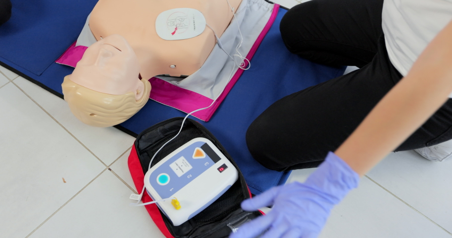 CPR training medical procedure workshop. Demonstrating chest compressions and use of AED automatic defibrillator on CPR doll Royalty-Free Stock Footage #1081465844