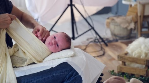 Tiny baby is swaddled before photographing. Professional photography of a baby in the studio, behind the scenes. Newborn baby is being prepared for photography