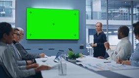 Office Conference Room Meeting Presentation: Beautiful Businesswoman Talks, Uses Green Screen Chroma Key Wall TV. Digital Entrepreneur Presents e-Commerce Product to Group of Multi-Ethnic Investors