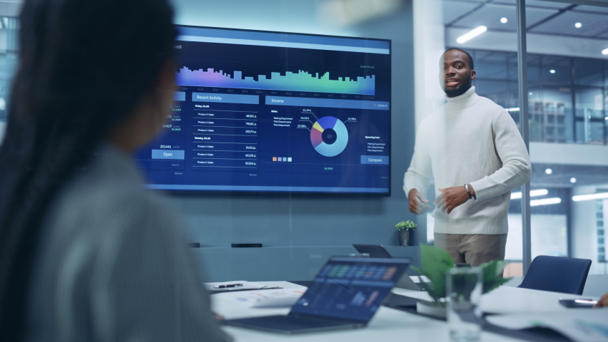 Diverse Modern Office: Motivated Black Businessman Leads Business Meeting with Managers, Talks, uses Presentation TV with Statistics, Charts, Big Data. Digital Entrepreneurs Work on e-Commerce Project | Shutterstock HD Video #1081470401