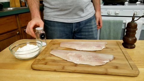 Home cooking - Seasoning two fillets of Walleye or Yellow Pike with salt getting fish ready top be batter in flour and cooked.