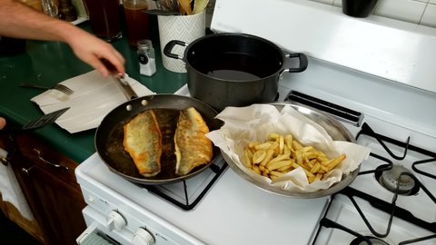 Home cooking -  Transferring cooked walleye or Yellow Pike fillets onto plate with paper to drain some grease or oil before serving with French fries