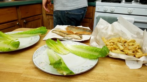 Home cooking - Preparing two serving of cooked walleye or Yellow Pike fillet and fried French fries on large plates with lettuce decoration.