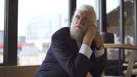 Tired businessman with grey beard thinking of work problem, feeling bored