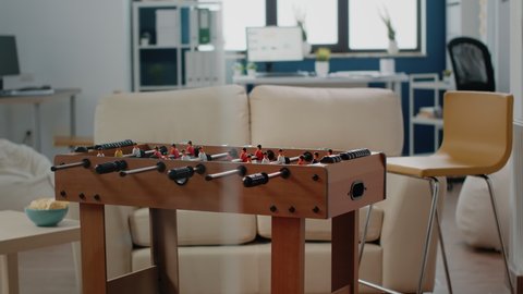Empty business office used for drinks and snacks after work. Nobody in workplace with foosball table to play football game, couch and chips to have fun with workmates after hours